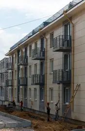 Первый из четырех домов практически готов – рабочие заканчивают покраску фасада